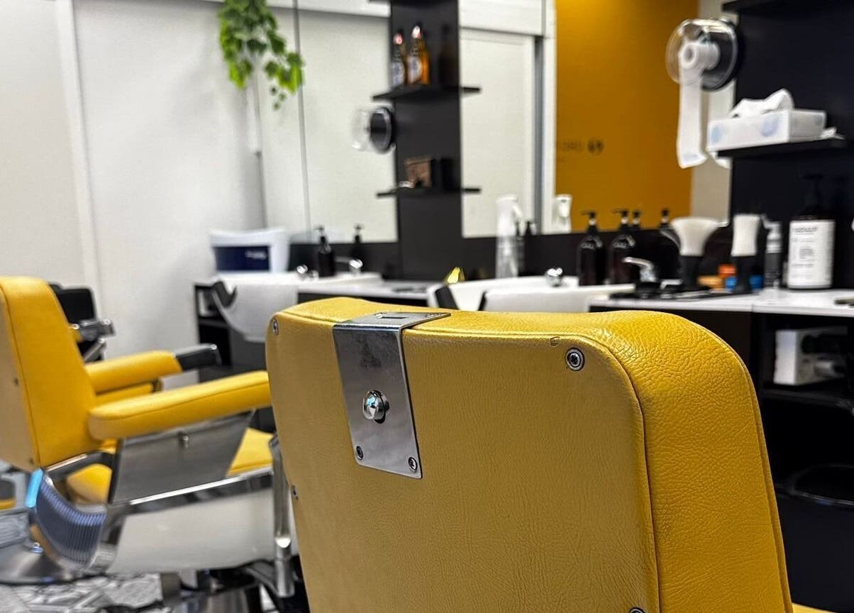 Interior de Barberia Oro Negro (Martinez Garrido) en Vigo, ES con silla amarilla y estantes bien organizados.