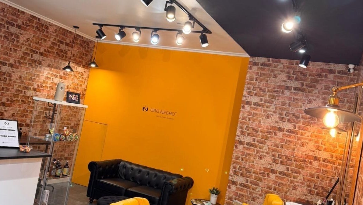 Interior de Barberia Oro Negro en Vigo, ES, con paredes de ladrillo y decoración moderna.