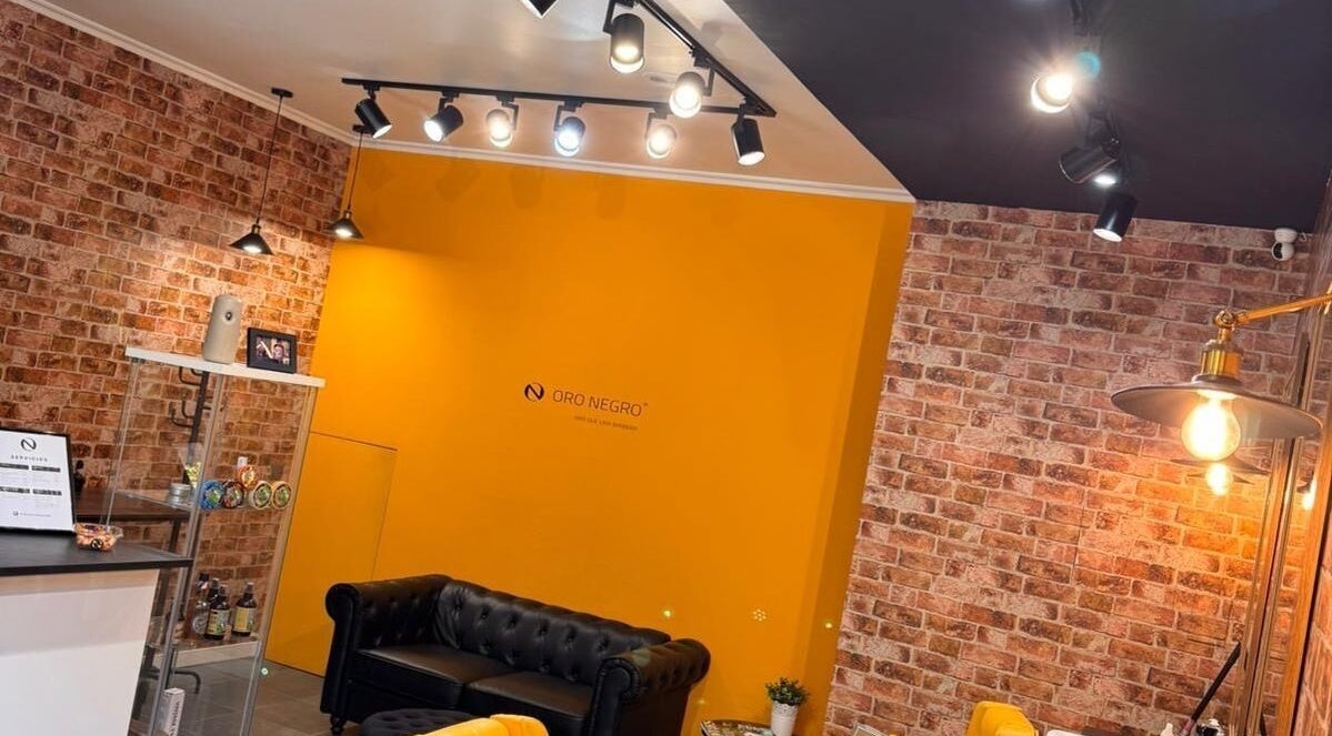 Interior de Barberia Oro Negro en Vigo, ES, con paredes de ladrillo y decoración moderna.