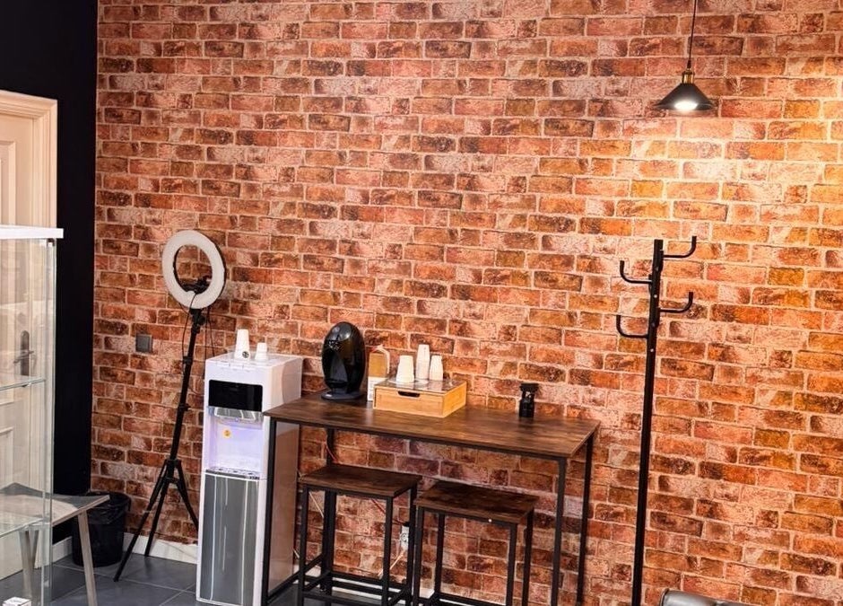 Interior acogedor en Barberia Oro Negro (salamanca), Vigo, ES, con pared de ladrillo y mesa de café.