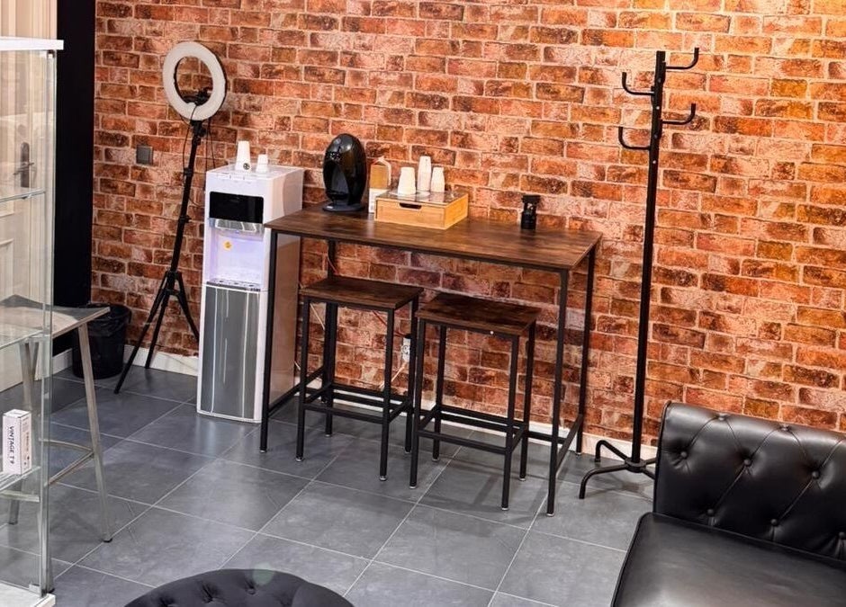 Zona acogedora en Barberia Oro Negro (Salamanca), Vigo, ES con ladrillo a la vista y sofás elegantes.