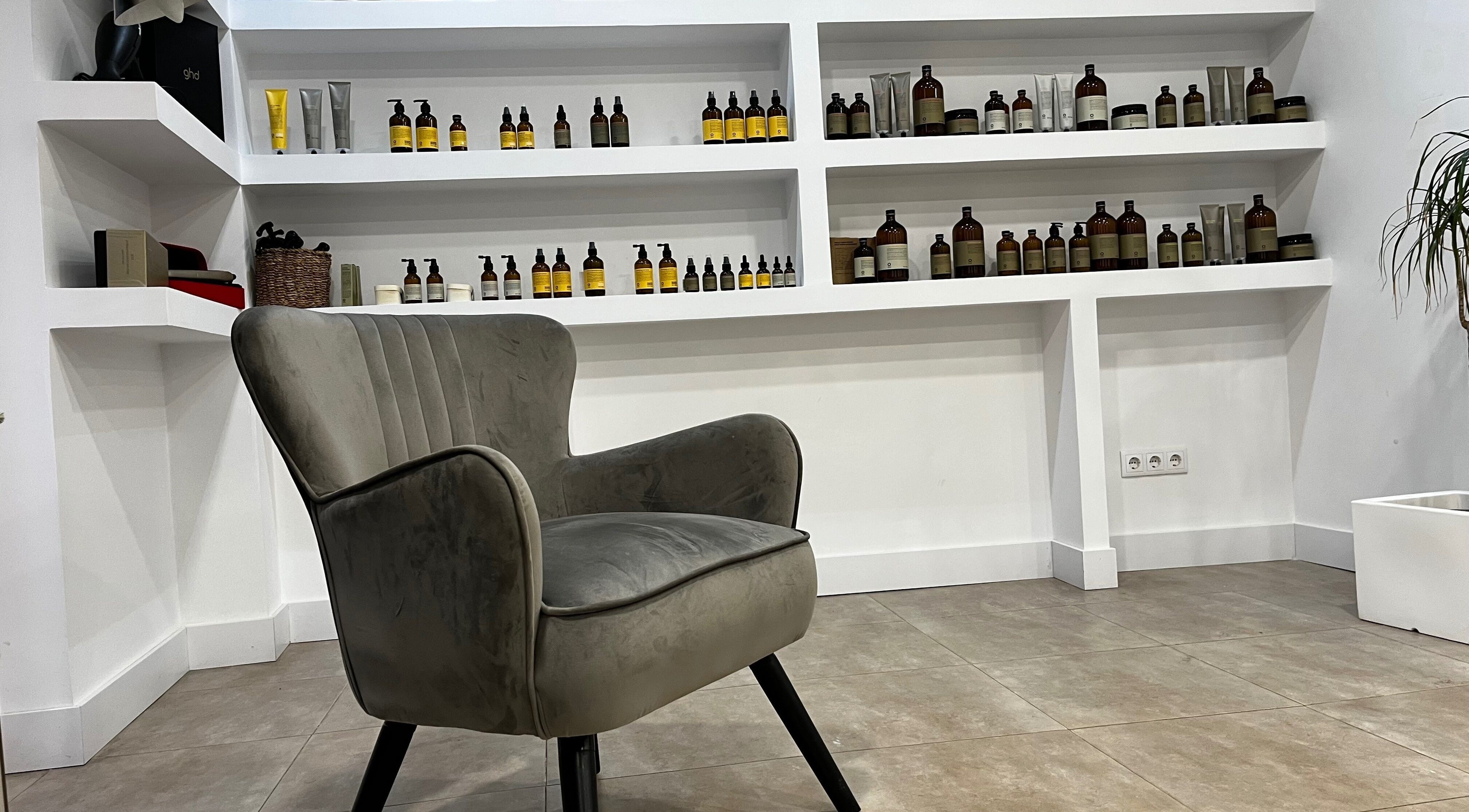 Silla moderna en R Estilistas, Alacant, Comunidad Valenciana, ES, con estanterías de productos de belleza.