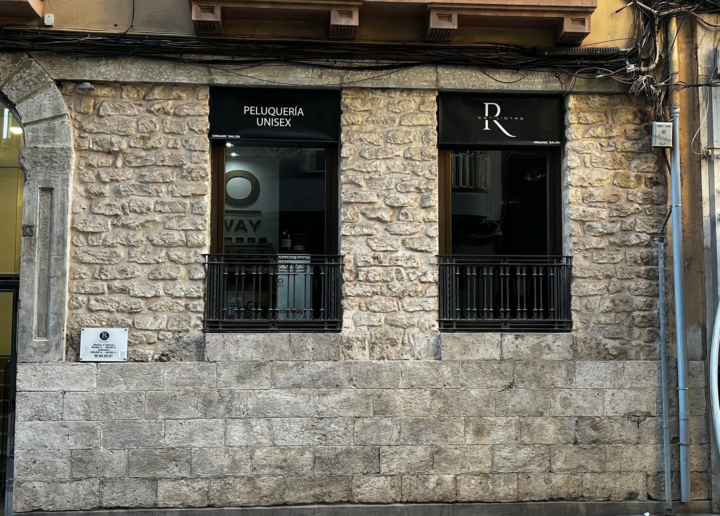 Fachada de R Estilistas en Alacant, Comunidad Valenciana, ES con diseño de piedra y ventanales elegantes.