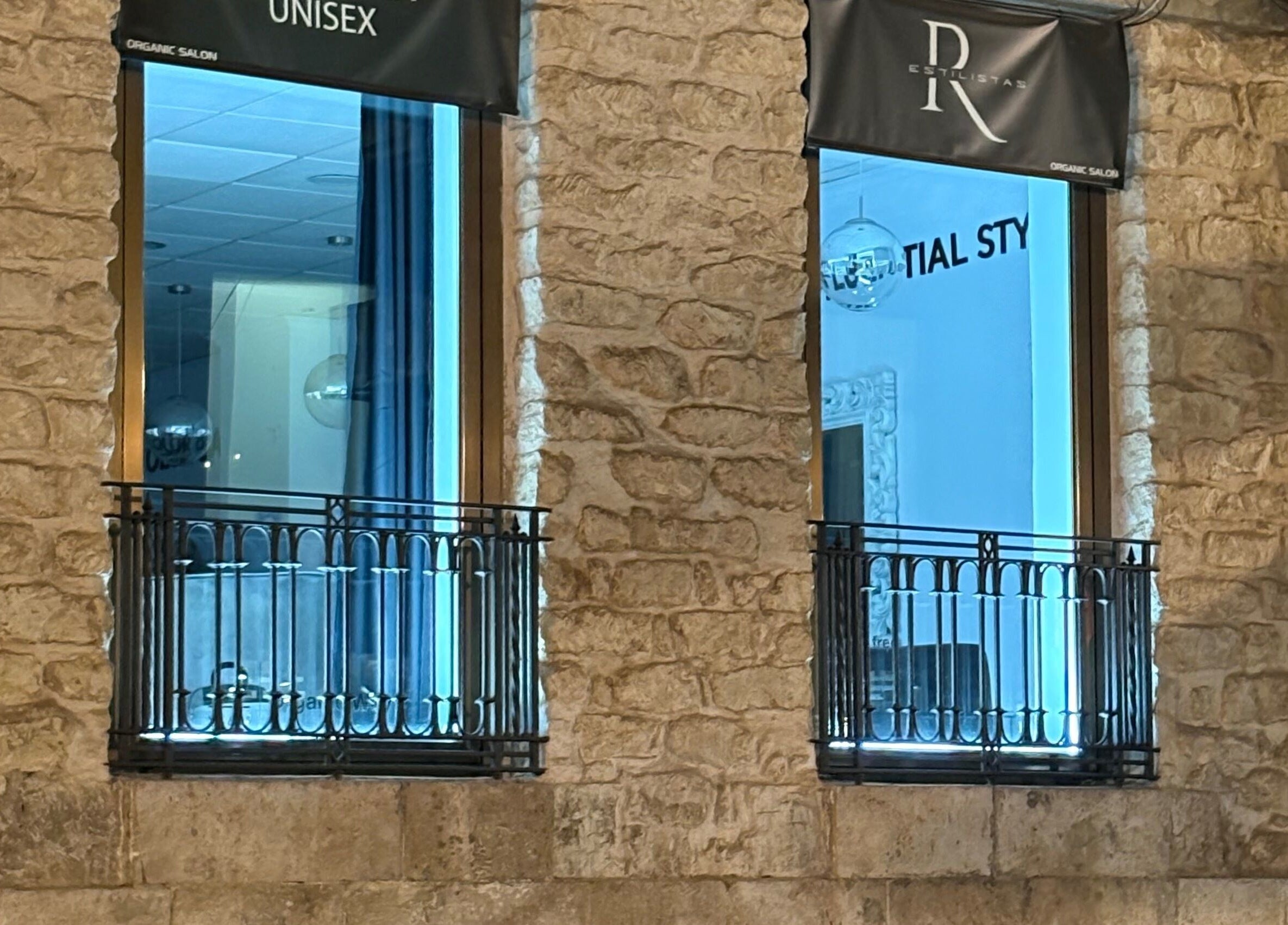 Ventana iluminada de R Estilistas en Alacant, Comunidad Valenciana, ES, destacando su fachada moderna y elegante.