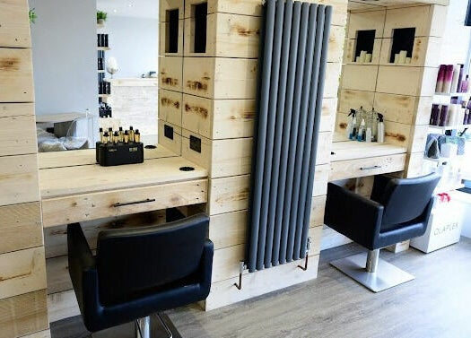 Modern hair styling stations at Marcia & Co, Freckleton, England, GB with sleek black chairs and wooden decor.