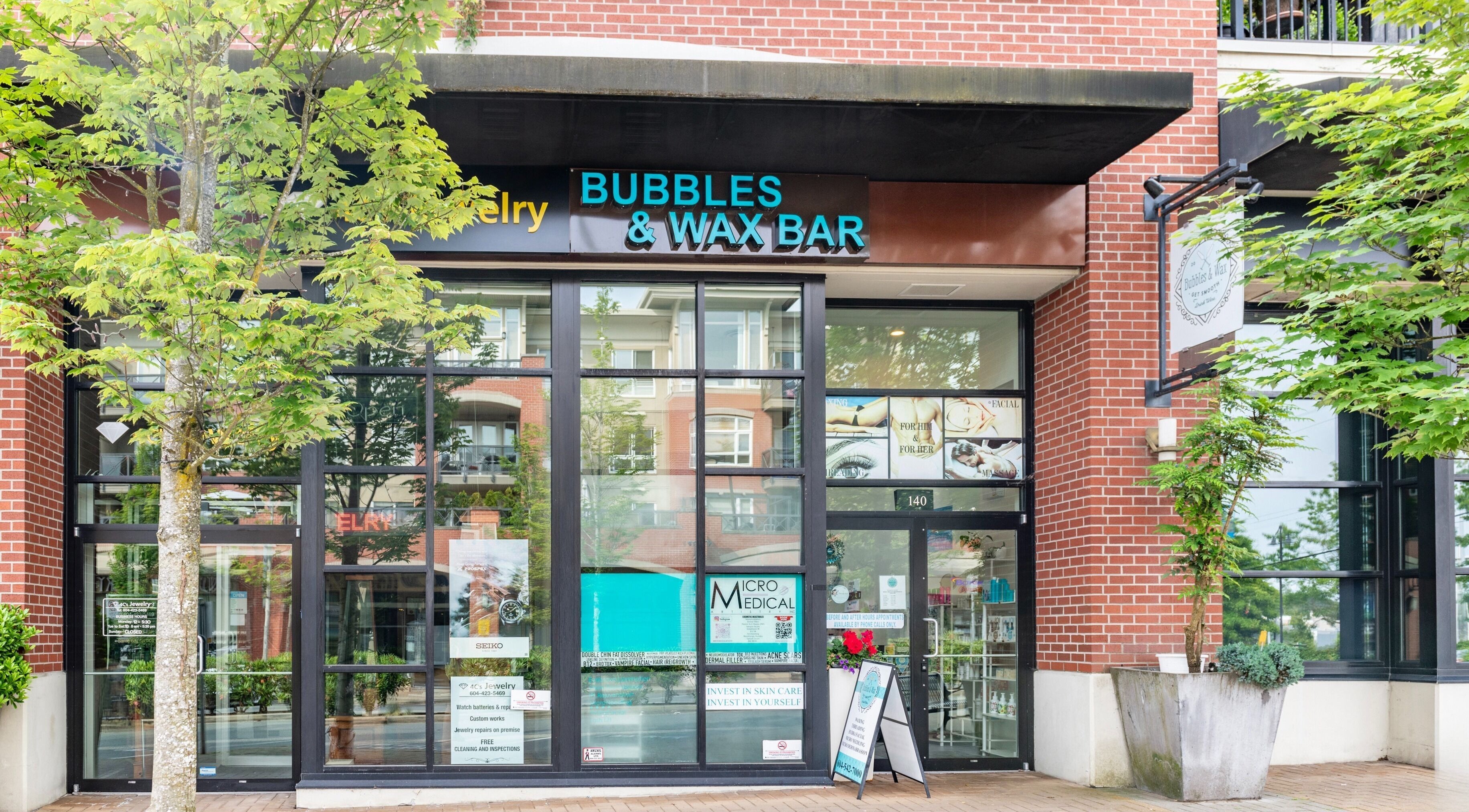 Front entrance of Bubbles and Wax Bar in Surrey, British Columbia, CA with glass windows and signage.
