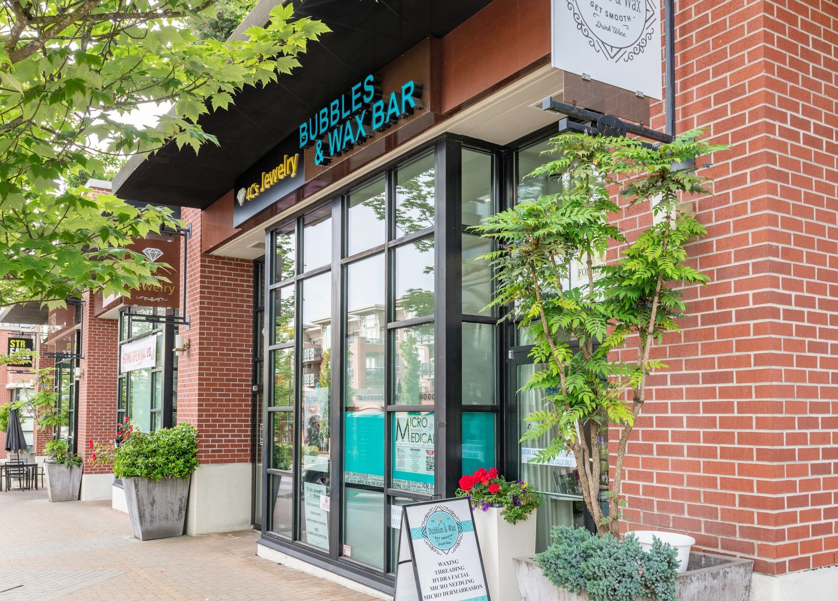 Exterior view of Bubbles and Wax Bar, Surrey, British Columbia, CA. Elegant brick facade with greenery.