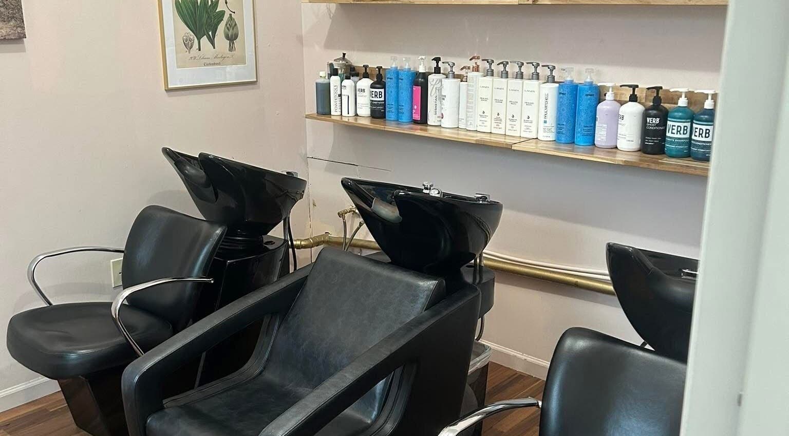 Elegant hair wash area at Haley Stapleton, Matthews, North Carolina, US, with modern black chairs and products.