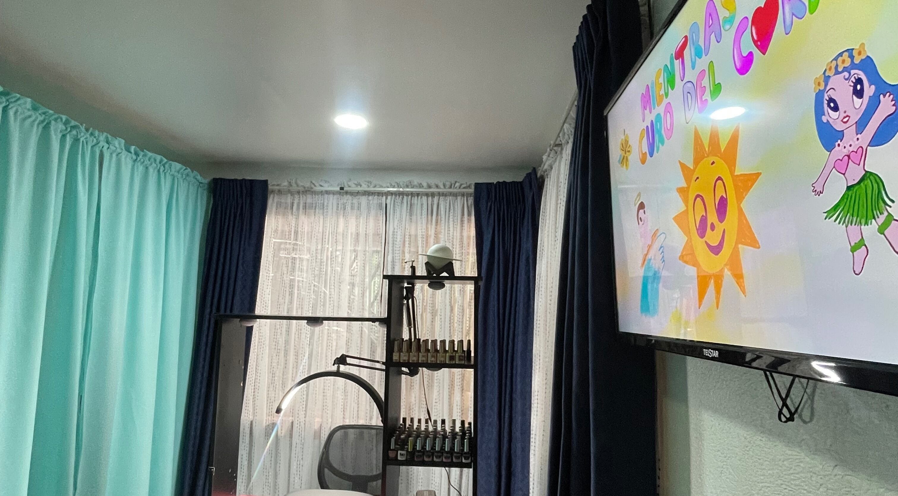 Interior de Saturno Nails en Concepción, Provincia De Cartago, CR con cortinas coloridas y pantalla ilustrativa.
