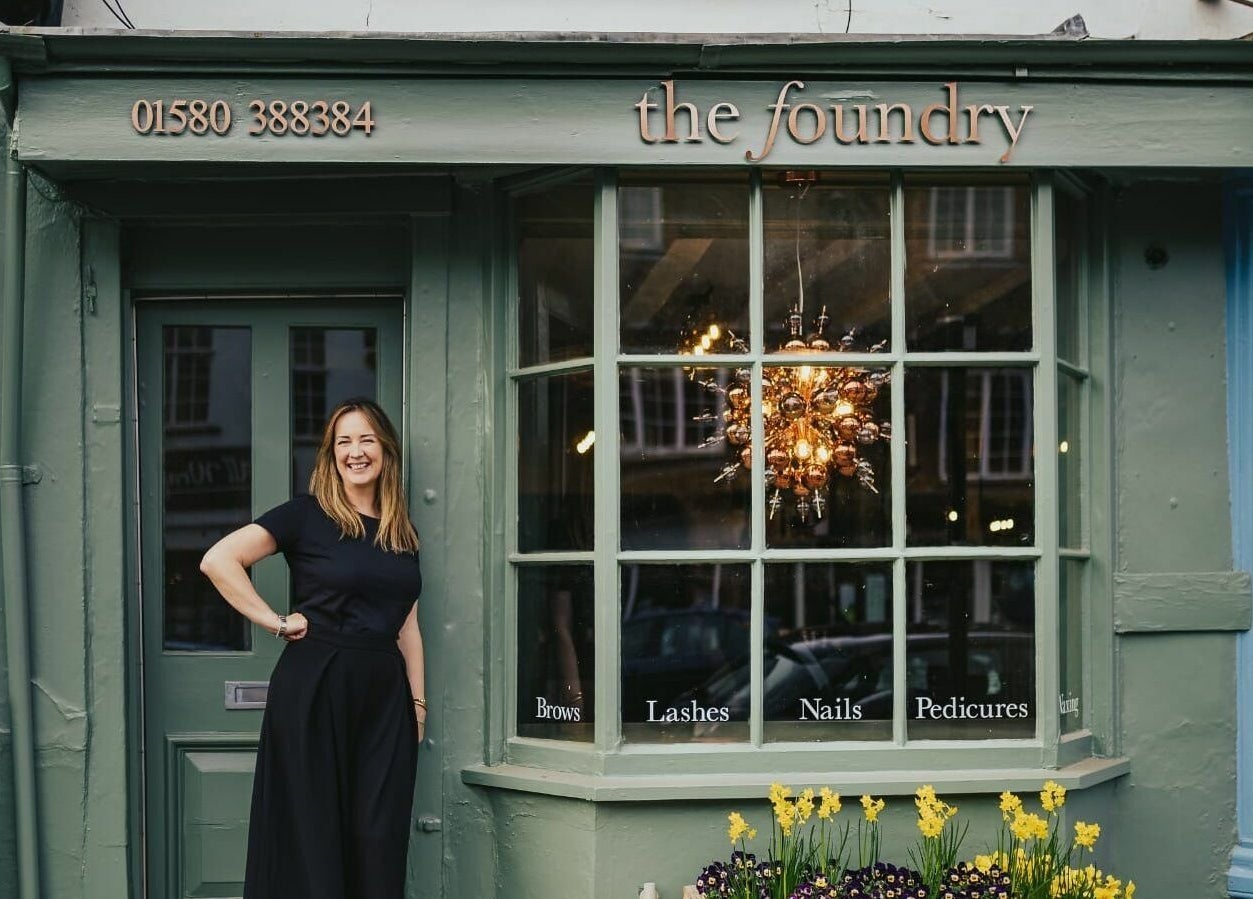 The Foundry, a beauty venue in Cranbrook, England, with a smiling staff member at the entrance.