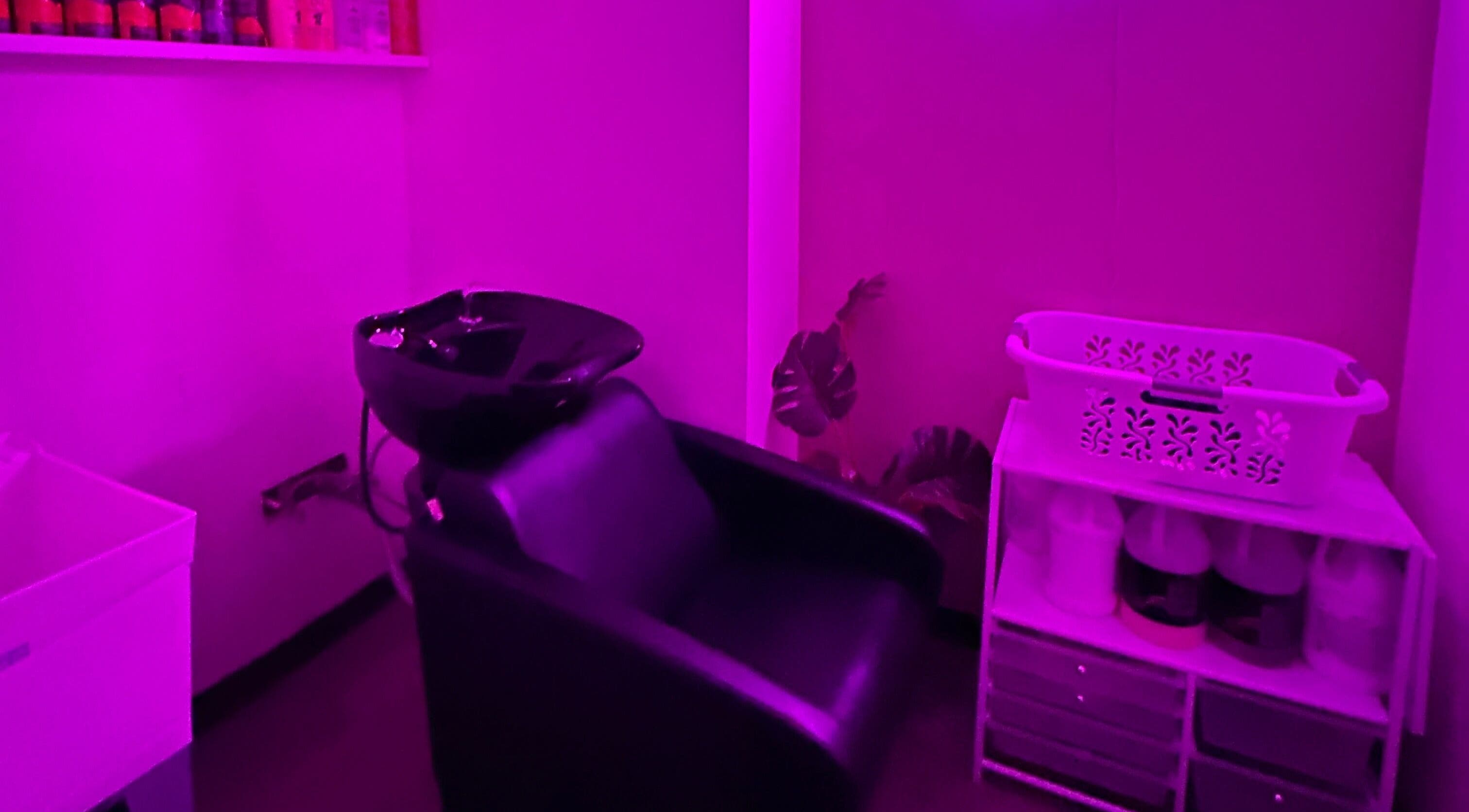 Cozy wash station at Dark Shugar Hair & Beauty Studios, Ellice, Winnipeg, Manitoba, CA, illuminated by purple light.