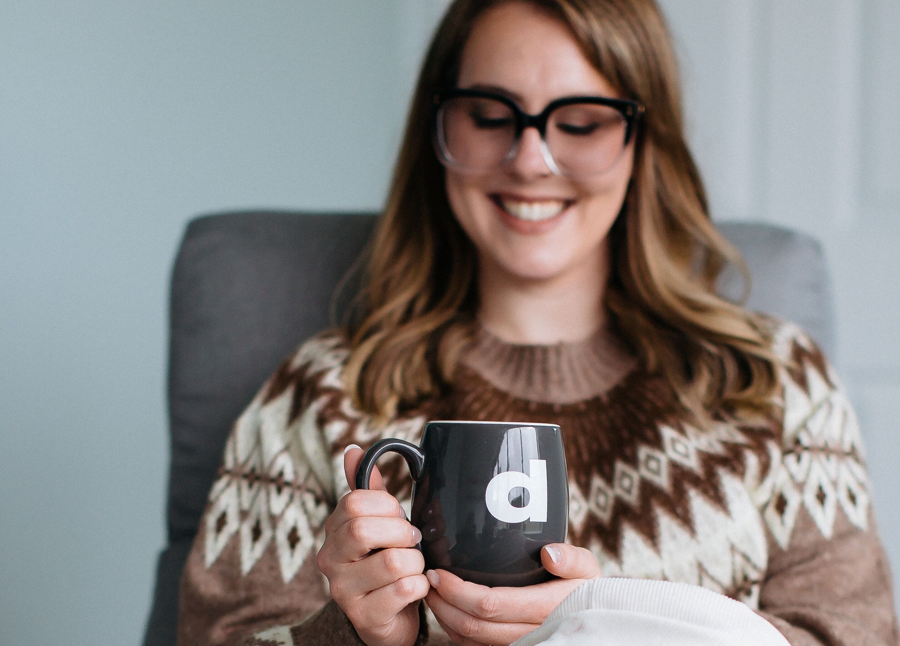 Woman enjoys a warm drink at Sugar and Stone Aesthetics, Kingston, Ontario, CA, highlighting a cozy atmosphere.