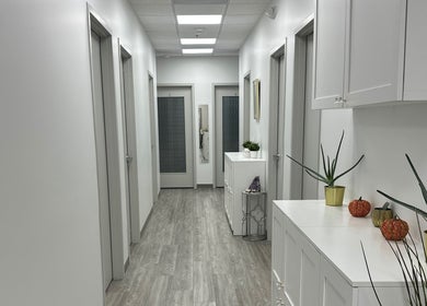 Bright hallway at Sole Radiance, Oakbrook, Illinois, US, lined with decor and plants on a white cabinet.