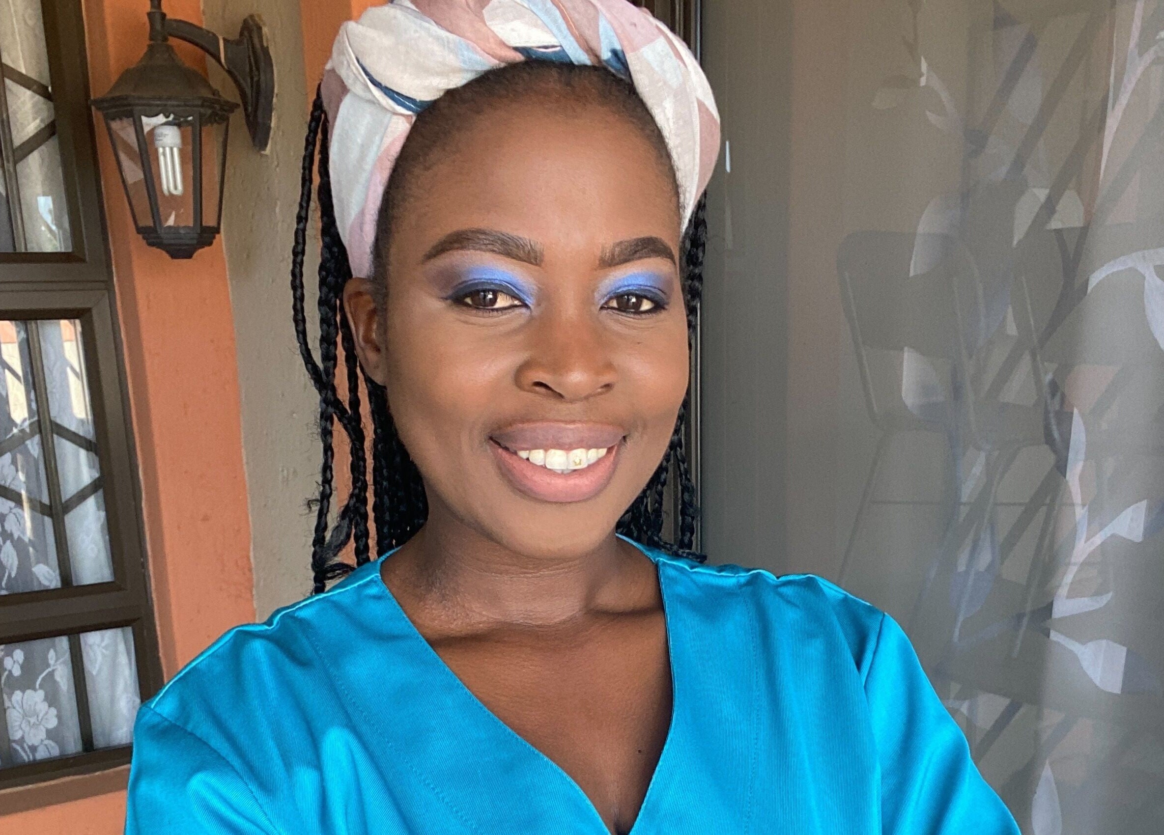 A smiling woman with vibrant blue eye makeup at Browed by Pat, Johannesburg, Gauteng, ZA.