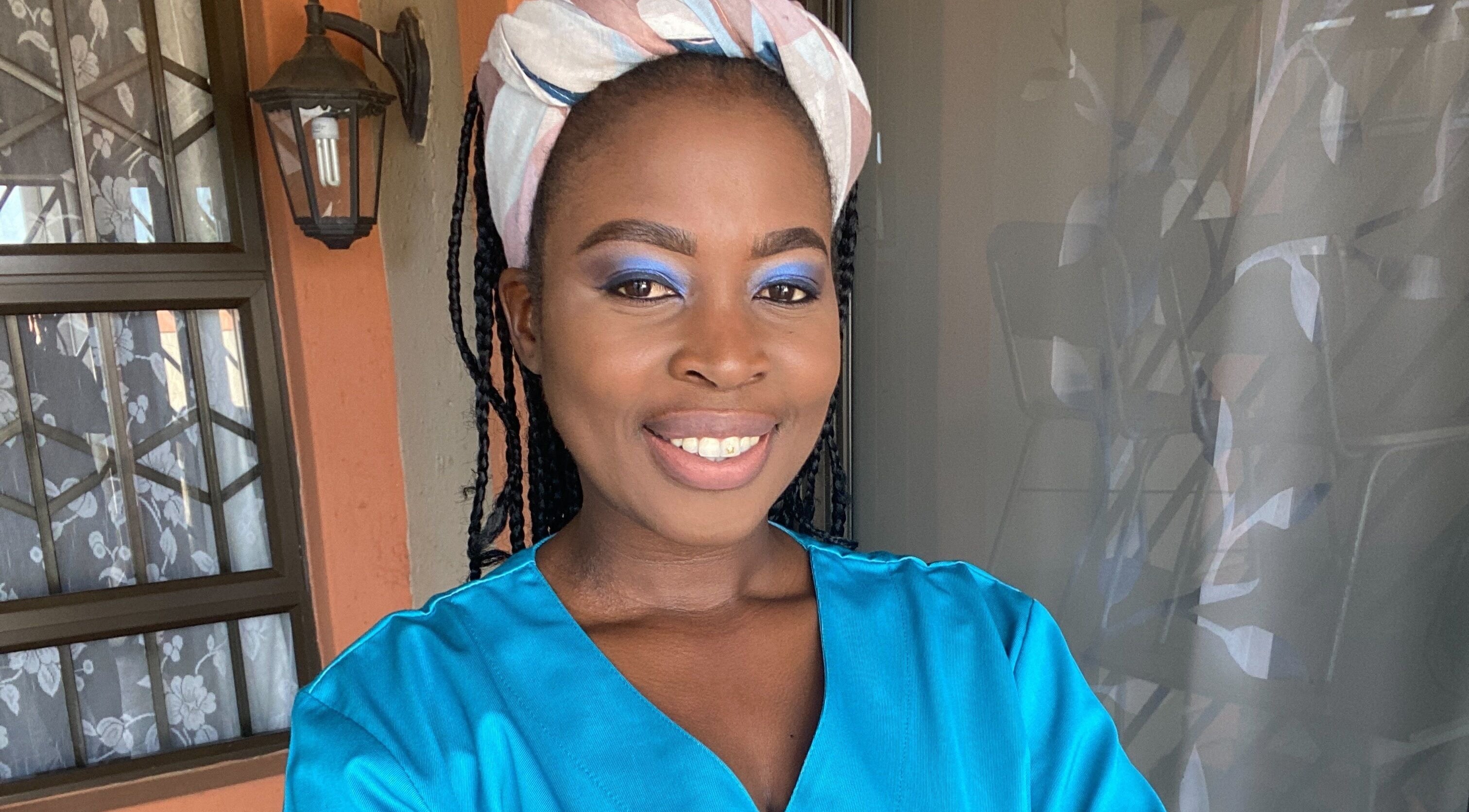 A smiling woman with vibrant blue eye makeup at Browed by Pat, Johannesburg, Gauteng, ZA.