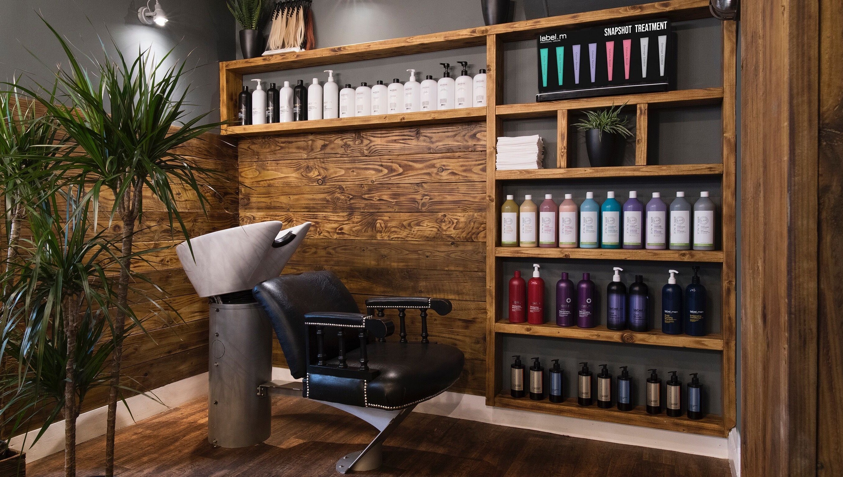 Modern salon interior at Karoliina Saunders_Hair in Highworth, England, GB with wooden shelves and vibrant hair products.
