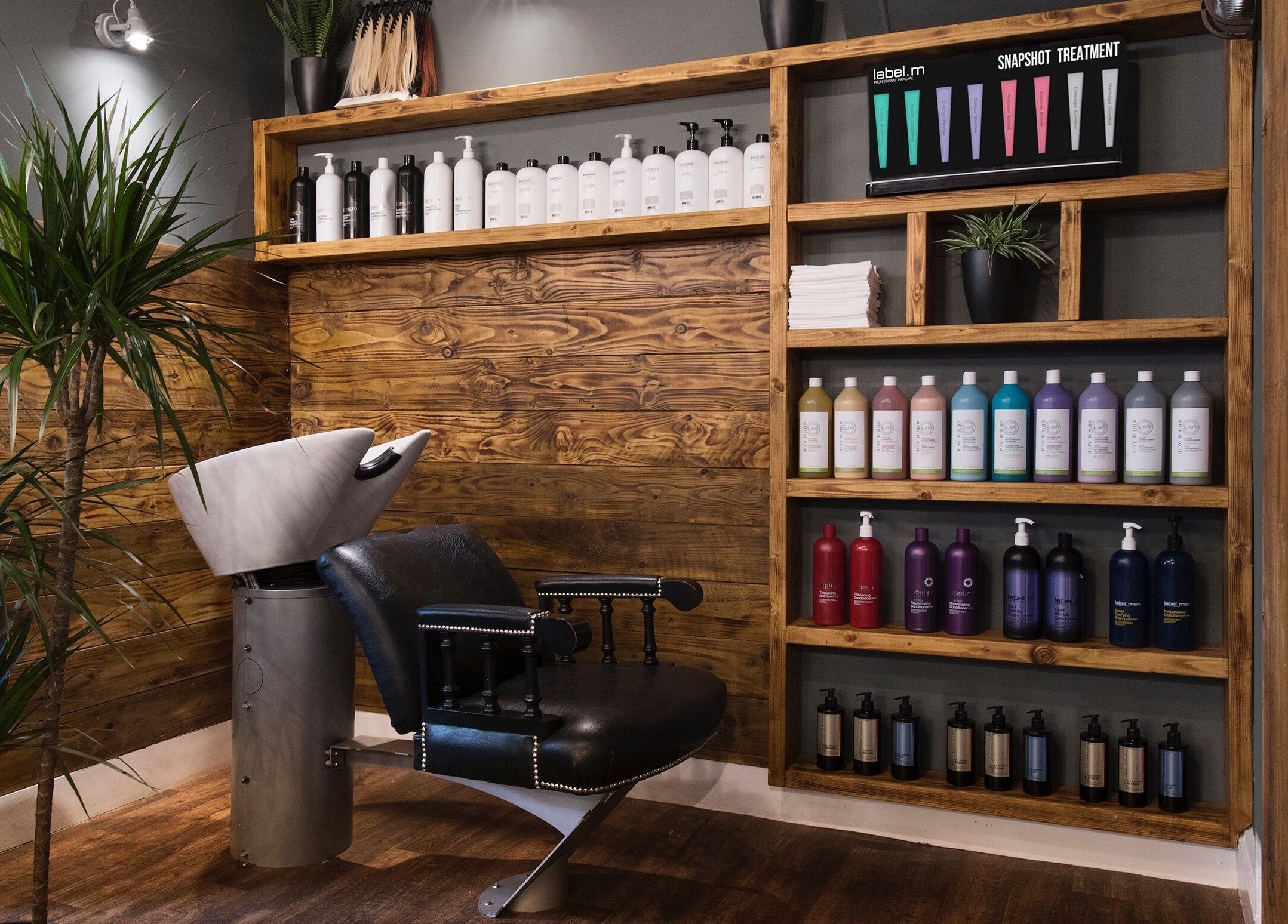 Modern salon interior at Karoliina Saunders_Hair in Highworth, England, GB with wooden shelves and vibrant hair products.