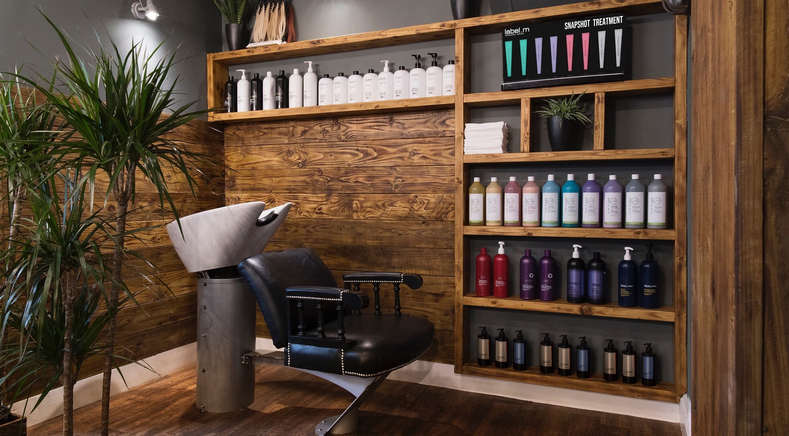 Modern salon interior at Karoliina Saunders_Hair in Highworth, England, GB with wooden shelves and vibrant hair products.