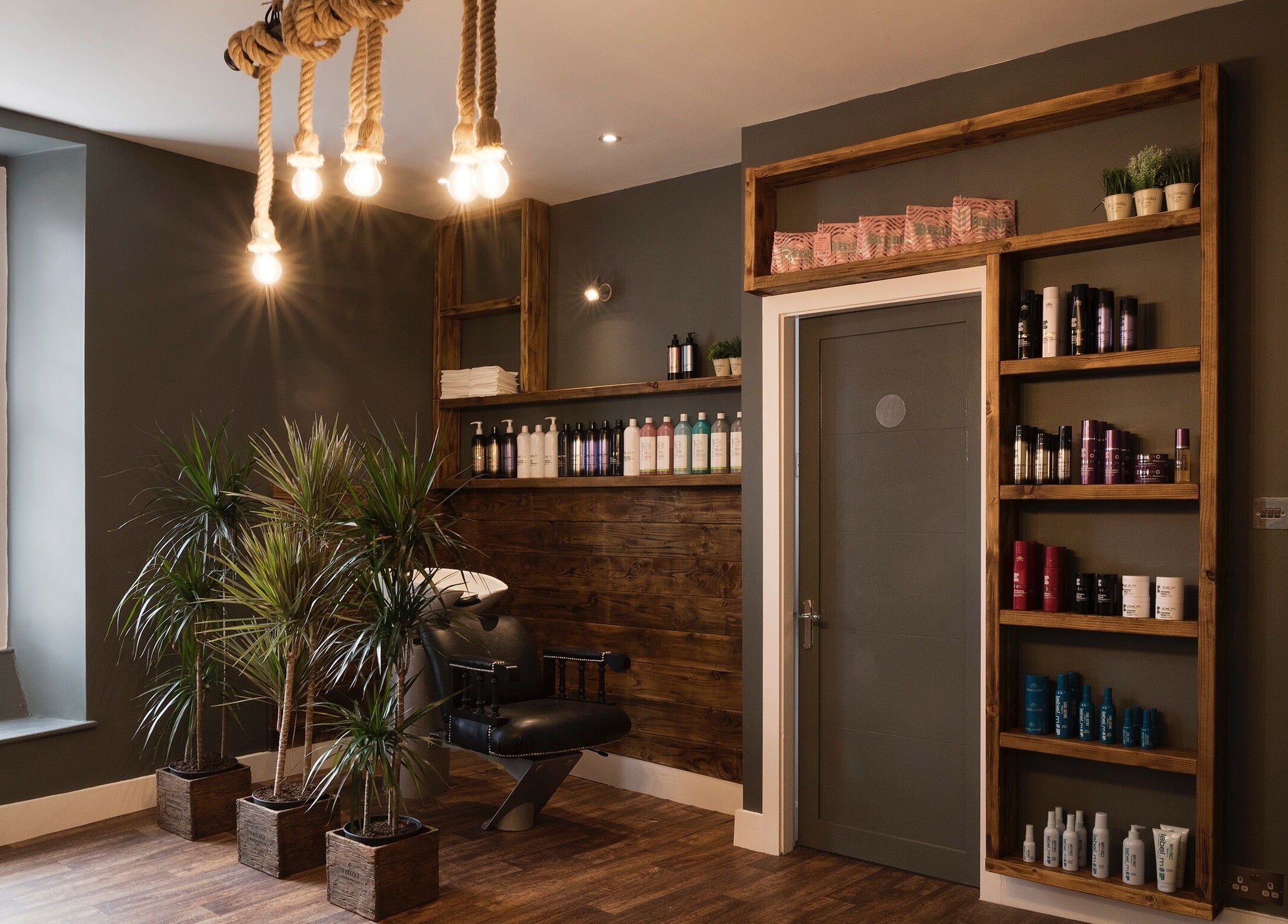 Contemporary interior of Karoliina Saunders_Hair salon in Highworth, England, featuring sleek styling chair and product shelves.