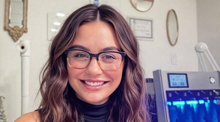 Smiling staff member at Jolie Skin Studio, Austin, Texas, US with treatment equipment in the background.