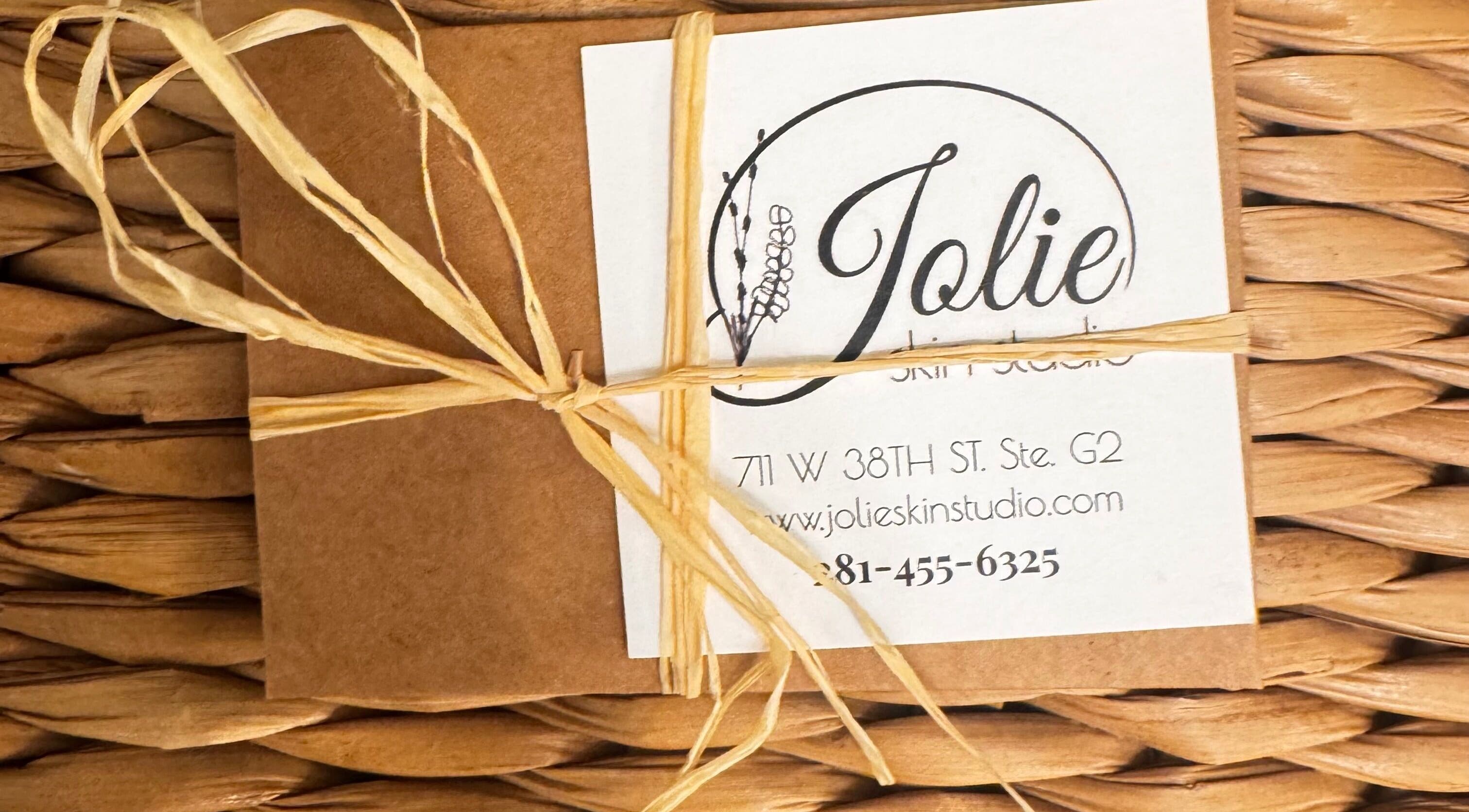Eco-friendly package with Jolie Skin Studio branding and address in Austin, Texas, US, tied with raffia.
