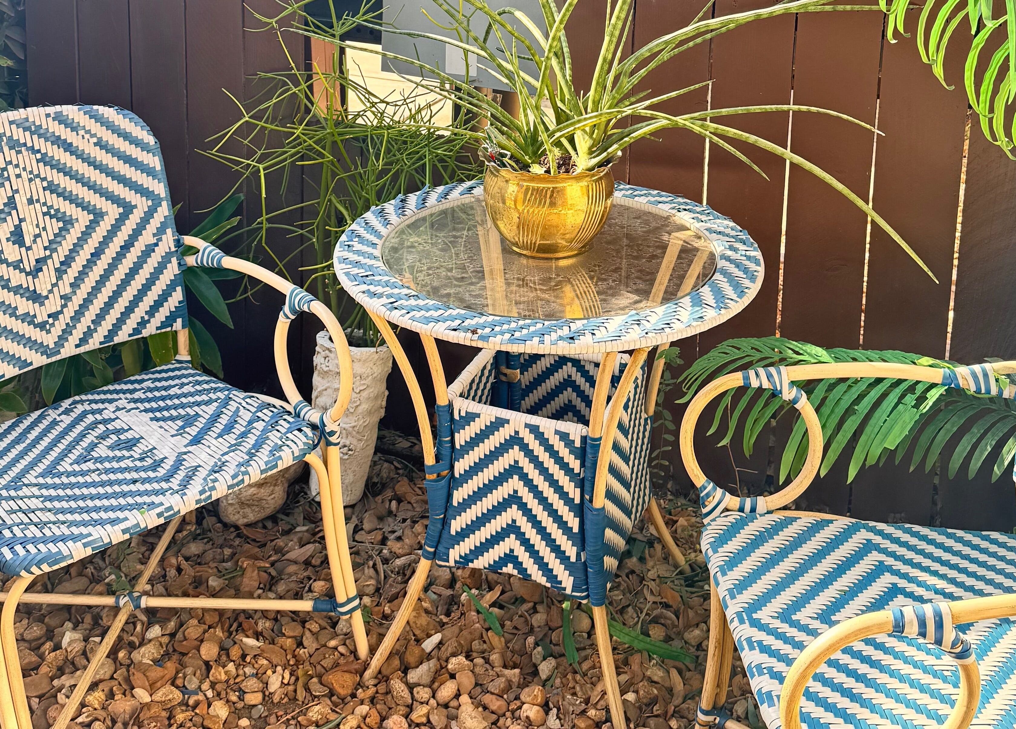 Relaxing outdoor seating area at Jolie Skin Studio, Austin, Texas, US with woven chairs and a glass-top table.