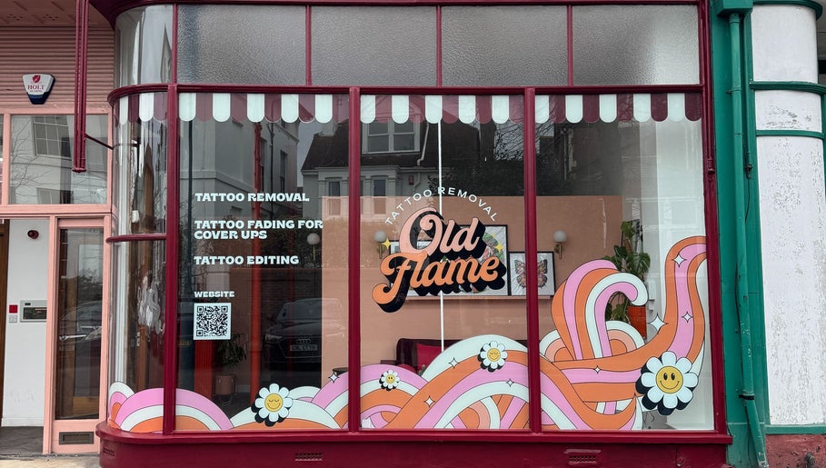 Vibrant storefront of Old Flame Tattoo Removal in Portsmouth, England, GB with colorful signs and designs.