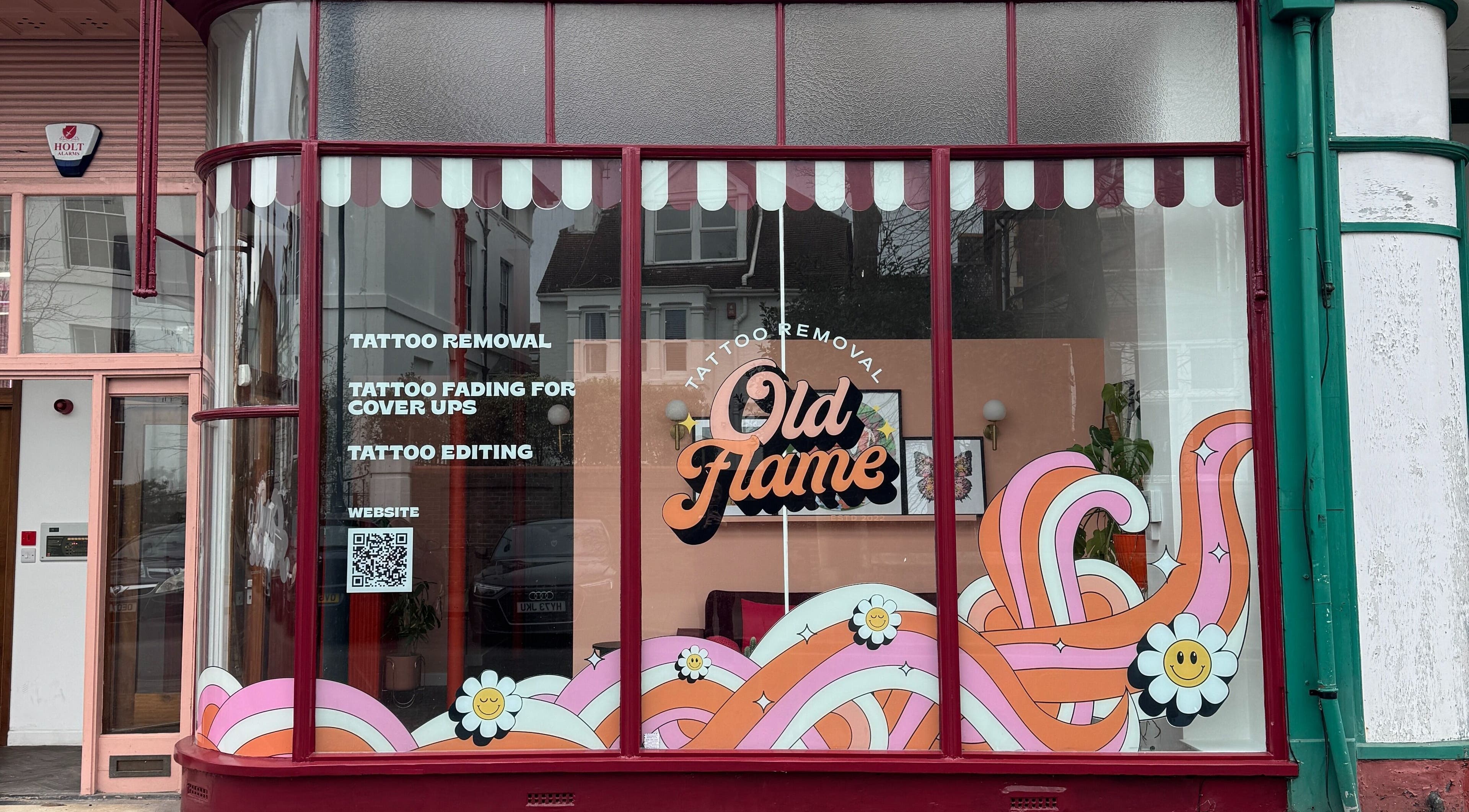 Vibrant storefront of Old Flame Tattoo Removal in Portsmouth, England, GB with colorful signs and designs.