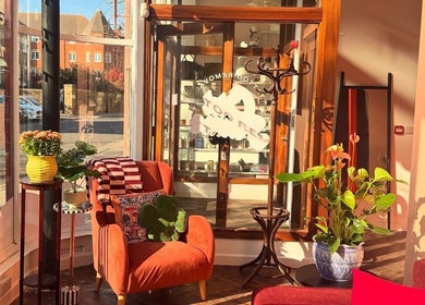 Sunny, inviting interior of Old Flame Tattoo Removal in Portsmouth, England, GB with warm seating and plants.