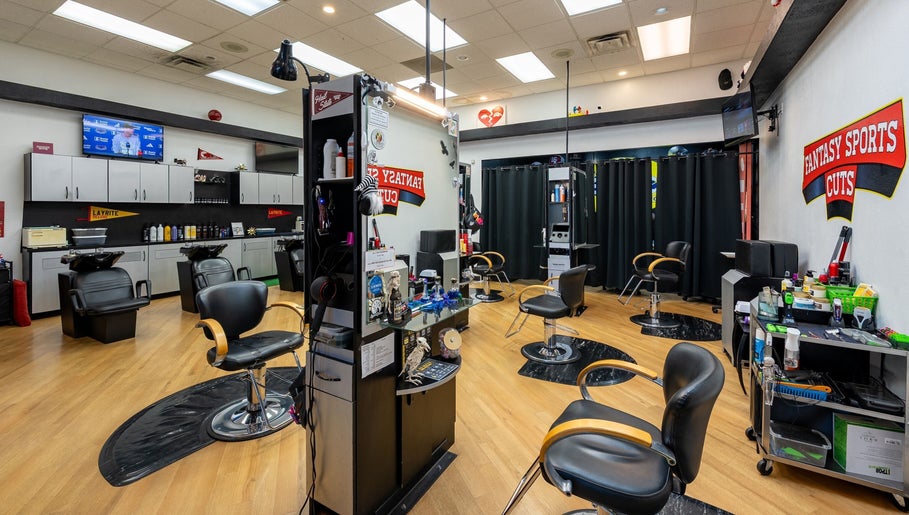 Interior view of Fantasy Sports Cuts, a modern barber shop in Fayetteville, Arkansas, US with sleek black chairs.