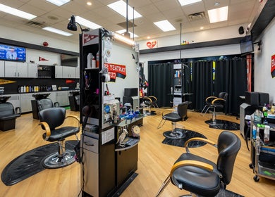 Interior view of Fantasy Sports Cuts, a modern barber shop in Fayetteville, Arkansas, US with sleek black chairs.