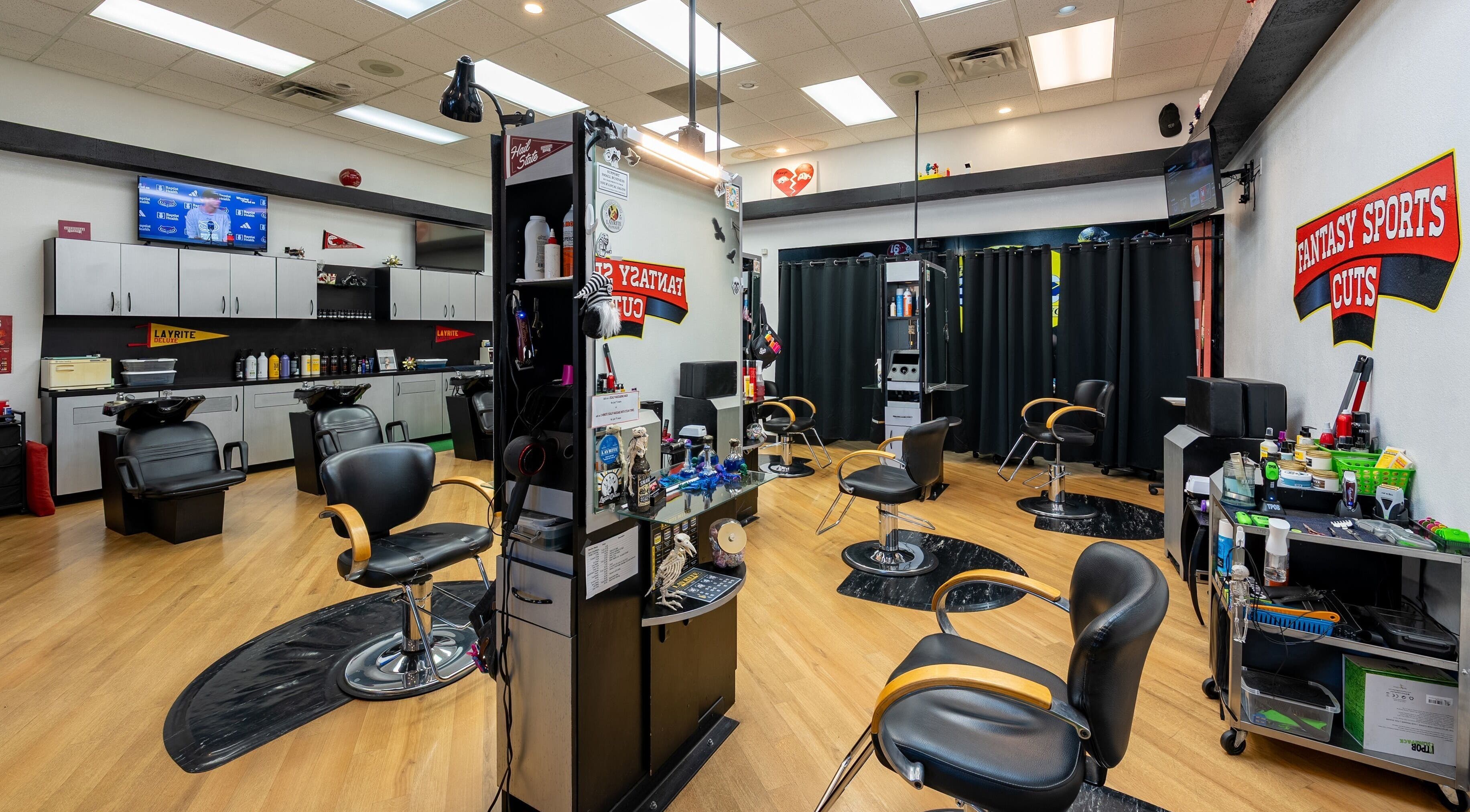 Interior view of Fantasy Sports Cuts, a modern barber shop in Fayetteville, Arkansas, US with sleek black chairs.