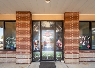 Entrance of Fantasy Sports Cuts, a barber shop in Fayetteville, Arkansas, US, featuring sports decals.