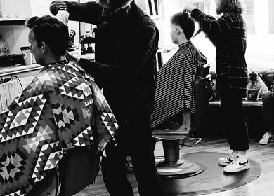 Stylish haircut in progress at Kings Barbers, Horsham, England, GB. Cozy interior with a lively atmosphere.