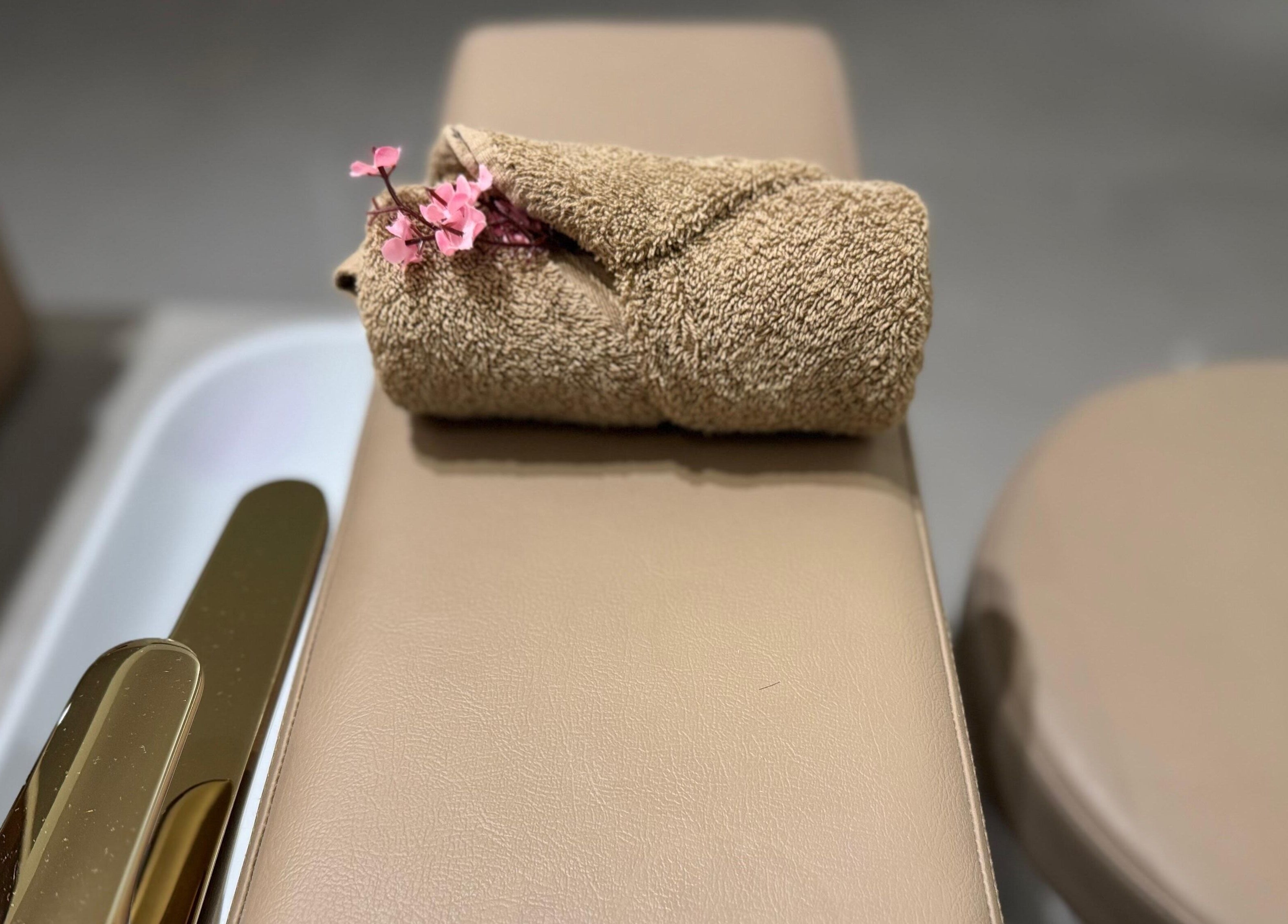 Luxurious spa bed at Abreez Beauty Salon, Sharjah, Sharjah, AE with a chic brown towel and pink flowers.
