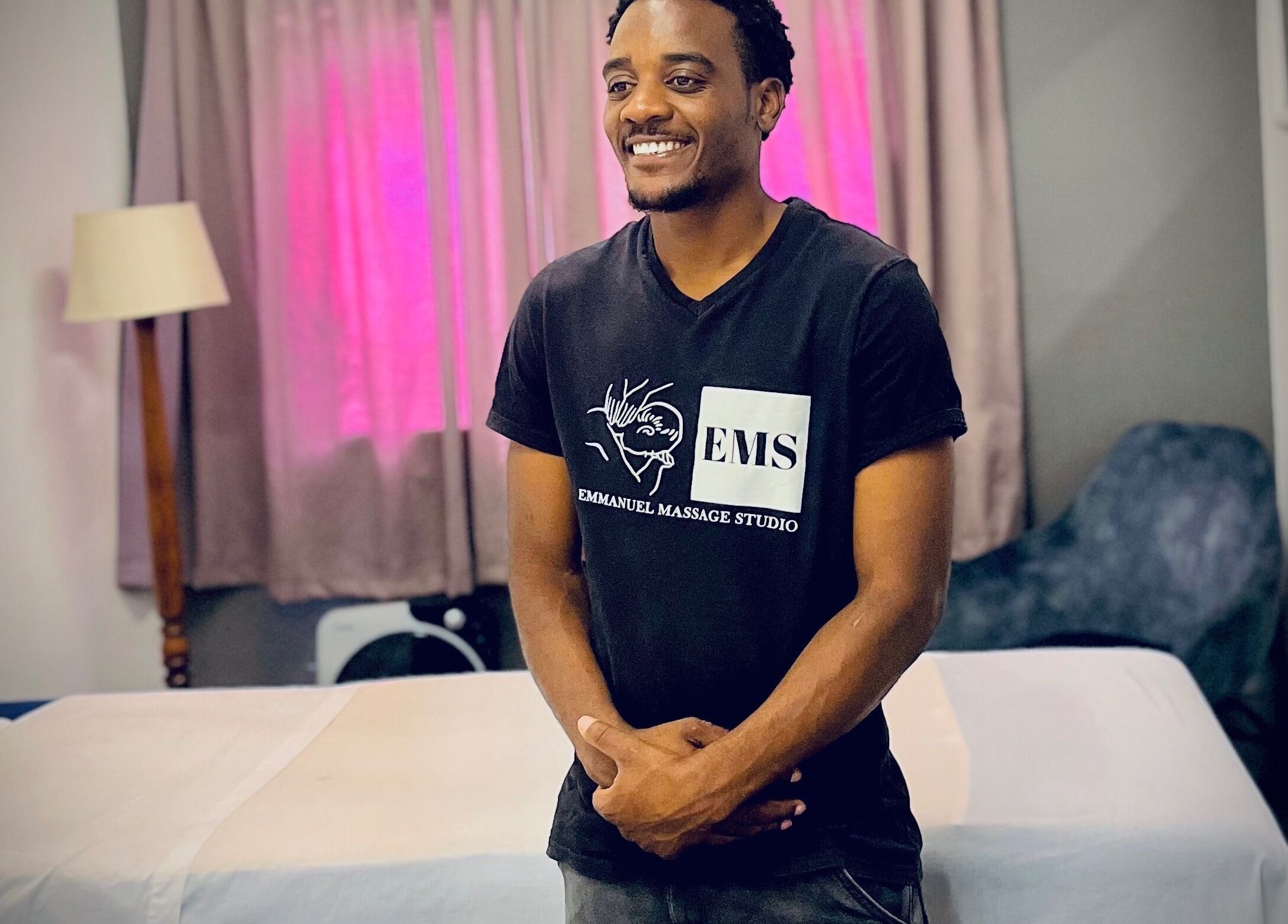 Professional at Emmanuel Massage Studio in Cape Town, Western Cape, ZA standing beside massage table.