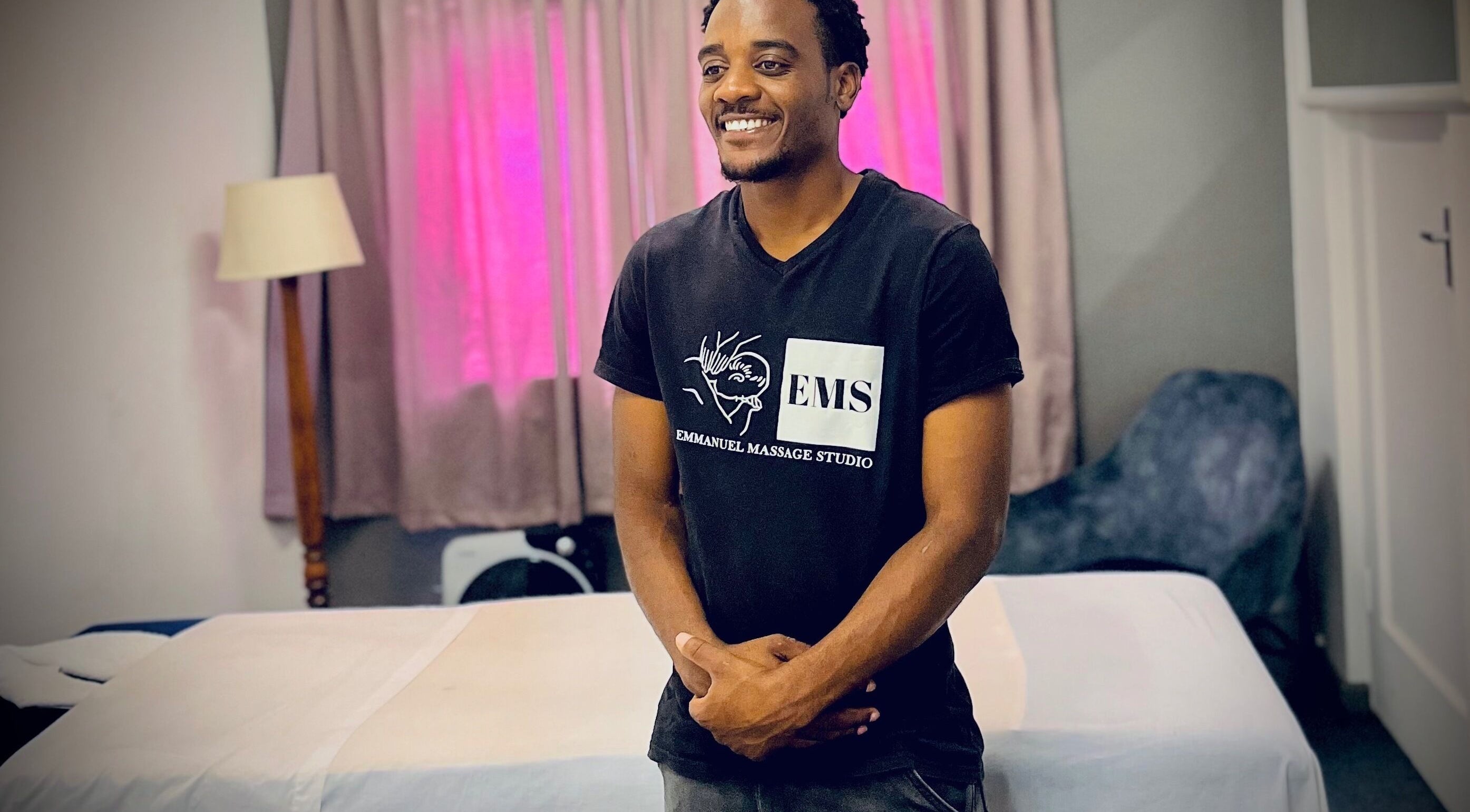 Professional at Emmanuel Massage Studio in Cape Town, Western Cape, ZA standing beside massage table.