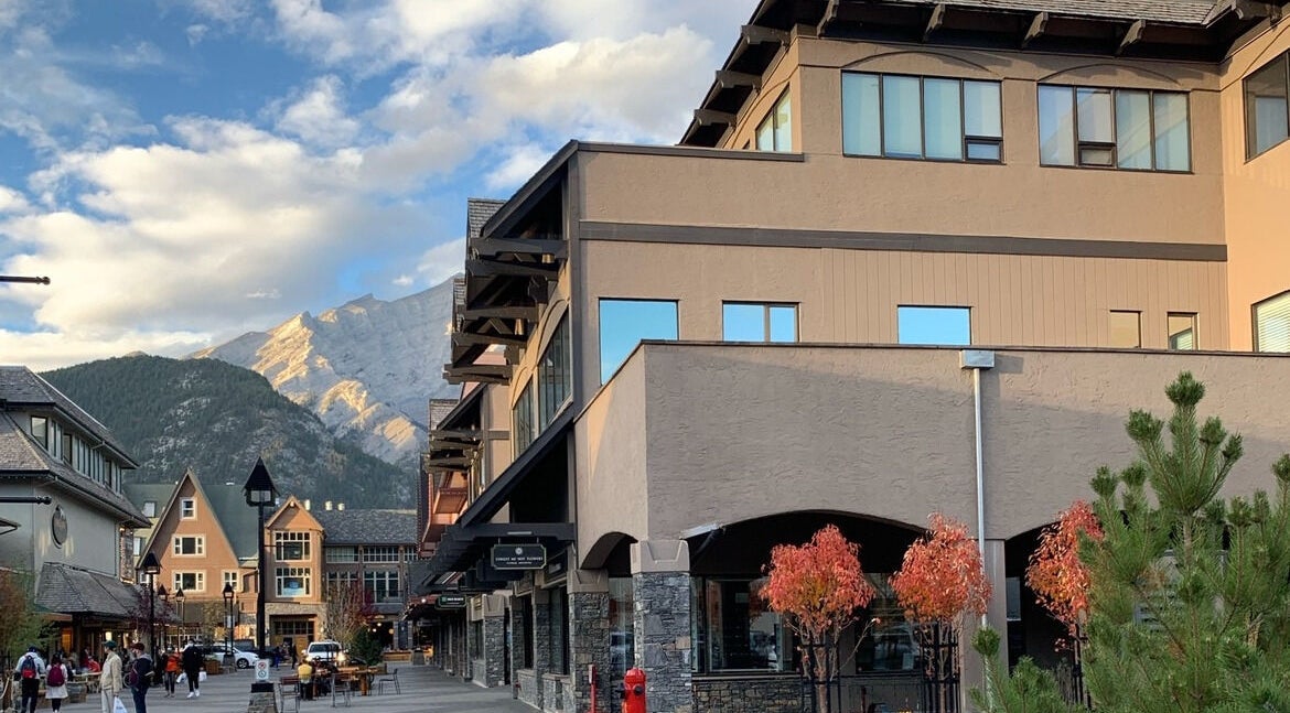 Scenic street view near Cedar & Sage Co, Banff, Alberta, CA, framed by mountains and clear skies.