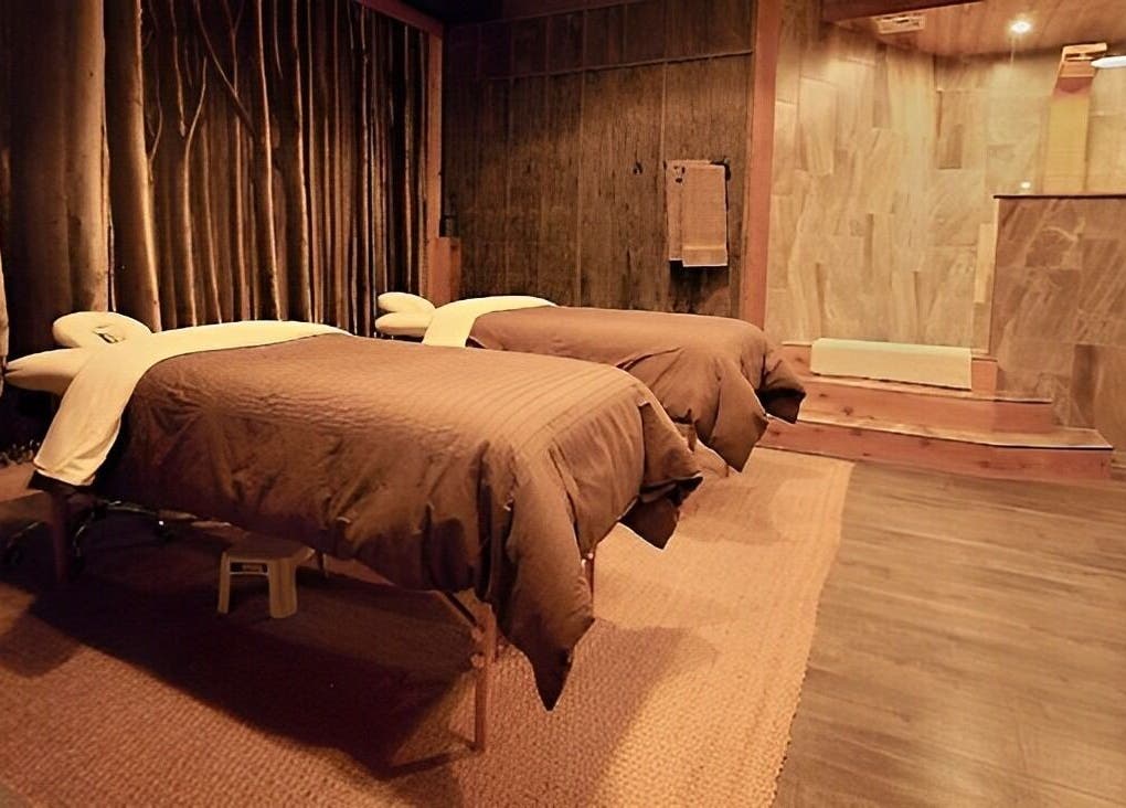 Tranquil spa room at Cedar & Sage Co, Banff, Alberta with two massage tables and warm lighting.