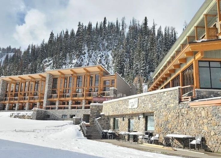 Cedar & Sage Sunshine Village in Banff, Alberta, CA, nestled by snowy mountains with rustic stone and wood design.