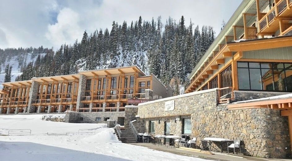Cedar & Sage Sunshine Village in Banff, Alberta, CA, nestled by snowy mountains with rustic stone and wood design.