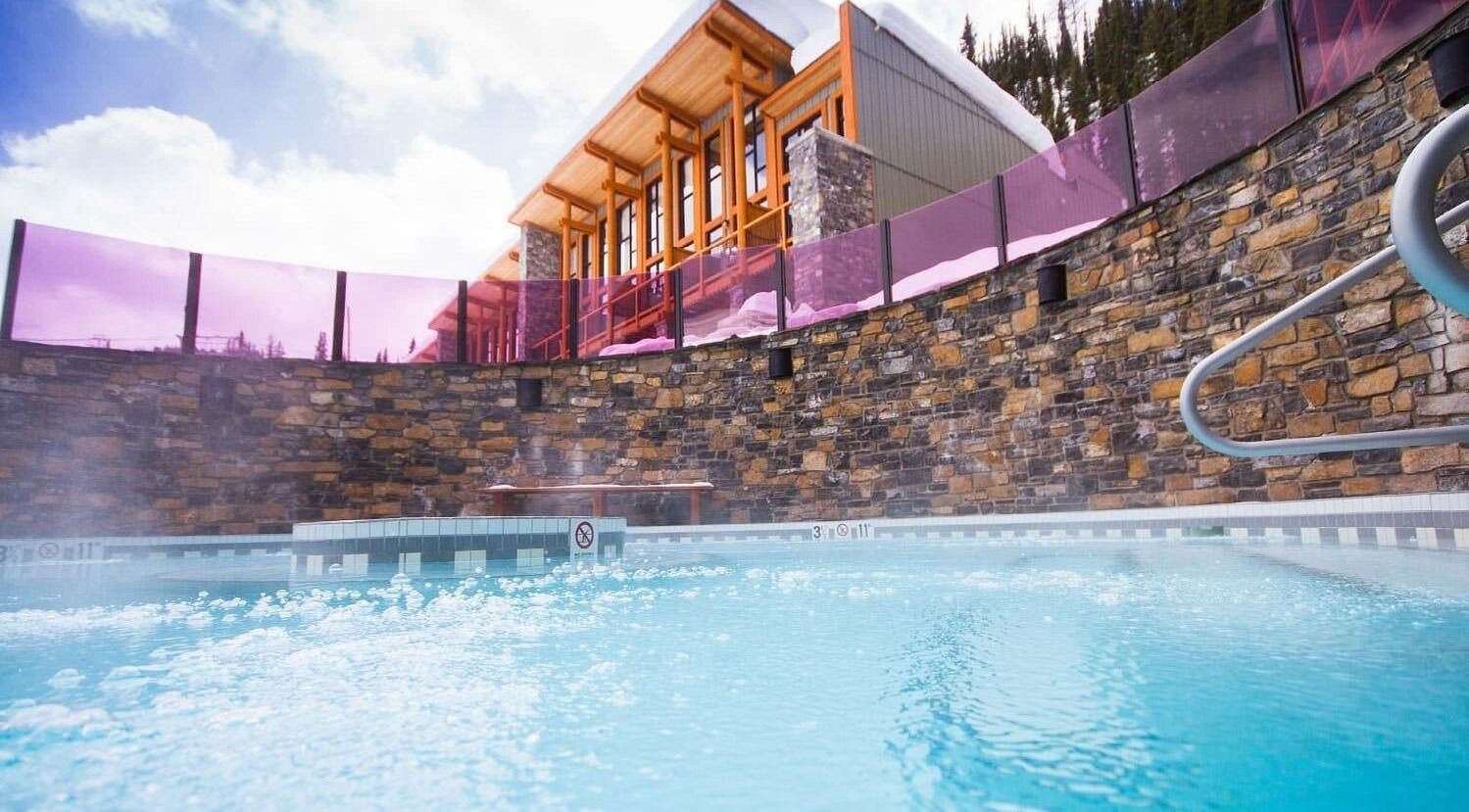 Luxurious outdoor hot tub at Cedar & Sage Sunshine Village, Banff, Alberta, CA, framed by rustic stone walls.