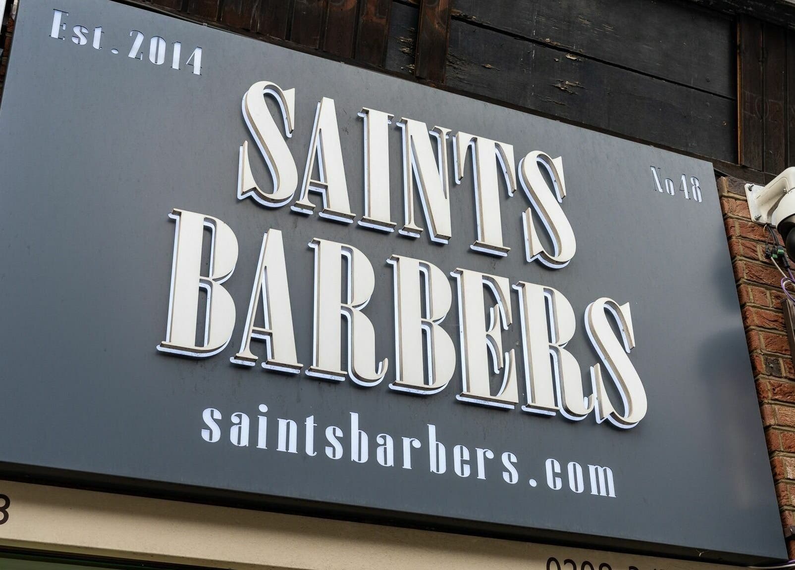 Signage of Saints Barbers Crouch End at London, England, GB, showcasing stylish logo.