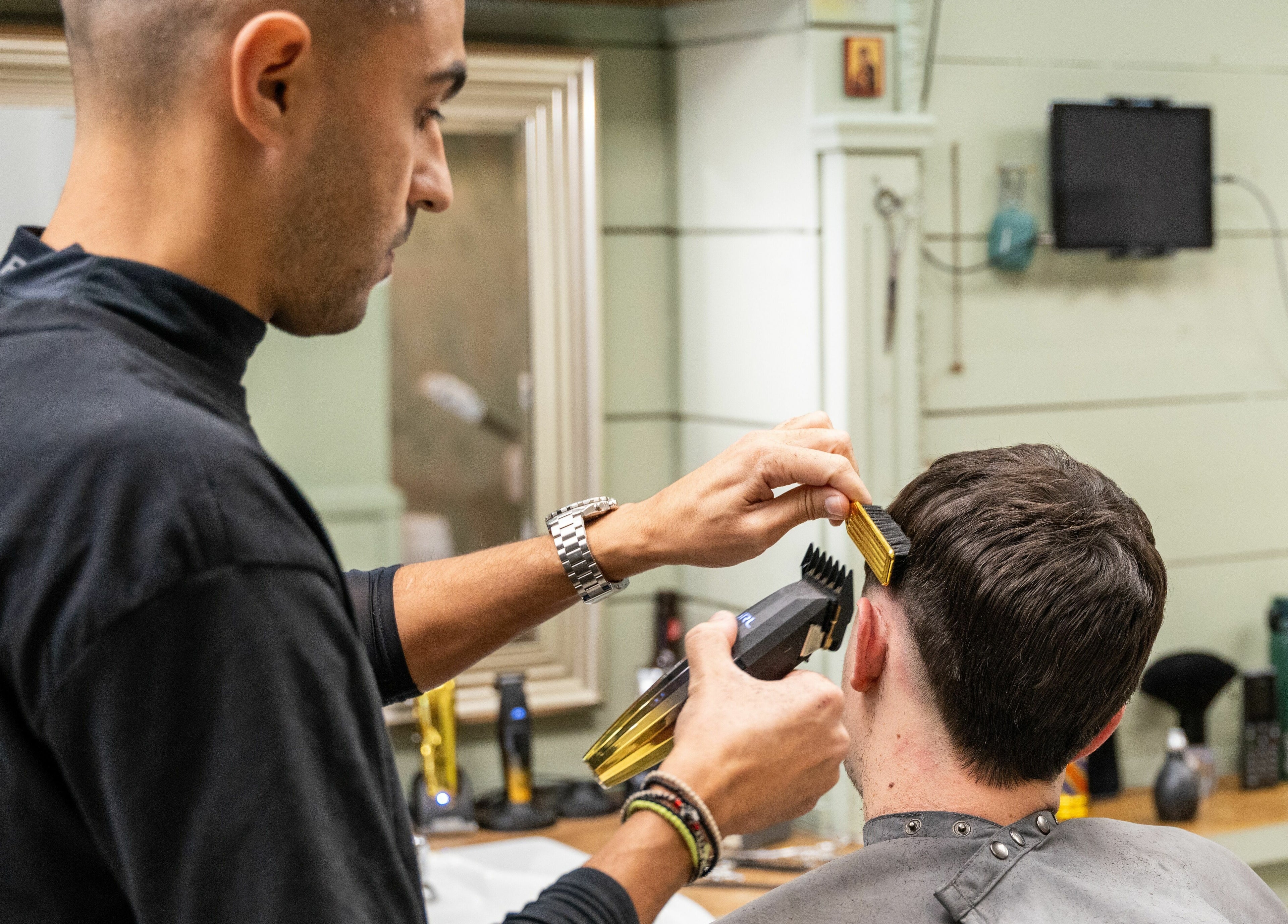 Barber expertly trims client’s hair at Saints Barbers Crouch End, London, England, GB.