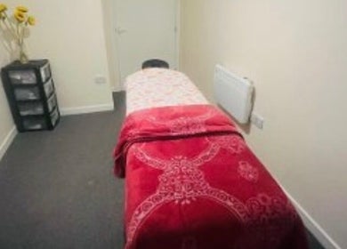 Peaceful treatment room at Glimmerbeauty, London, England, GB, with red decor and sunflowers.