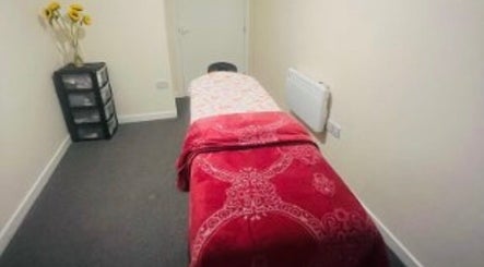 Peaceful treatment room at Glimmerbeauty, London, England, GB, with red decor and sunflowers.