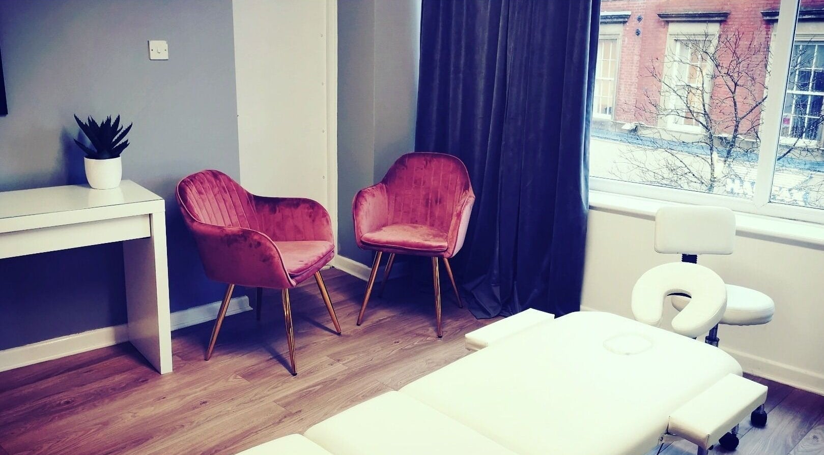 Relaxing treatment room at Glowmeup, Rochdale, England. Features stylish chairs and a cozy massage table.