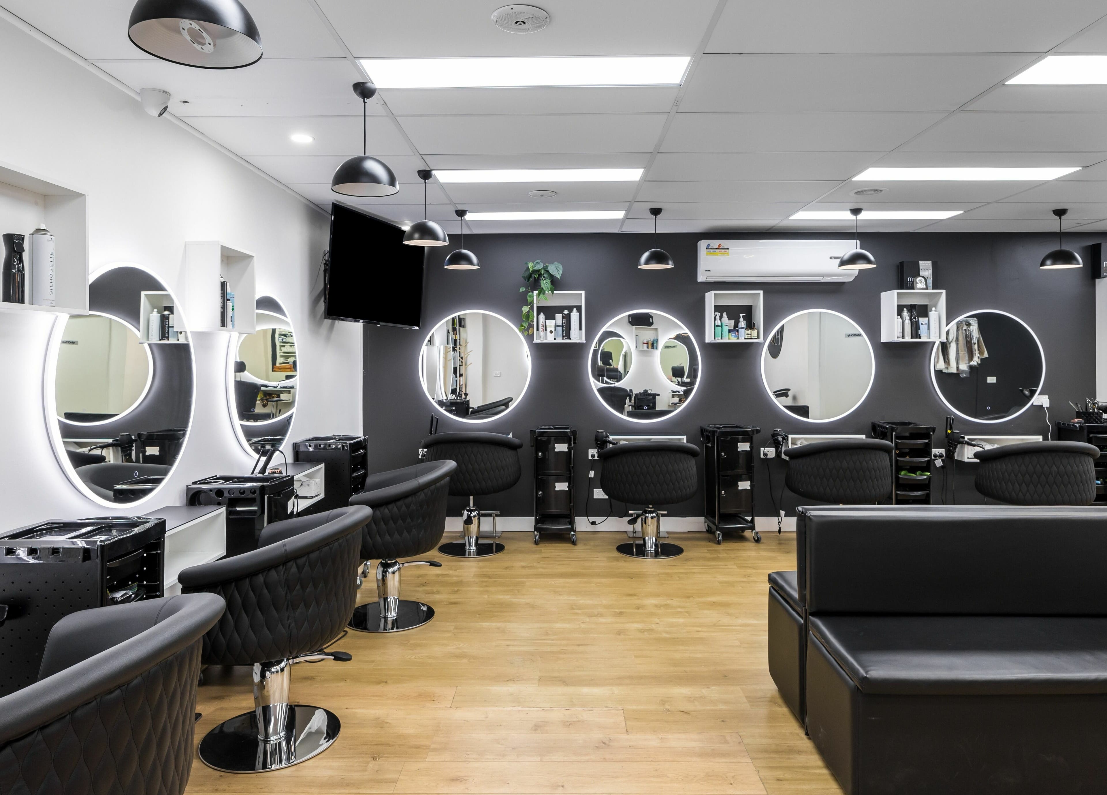 Interior view of V.I Hair salon in Melbourne, Victoria, AU with modern styling chairs and lit mirrors.