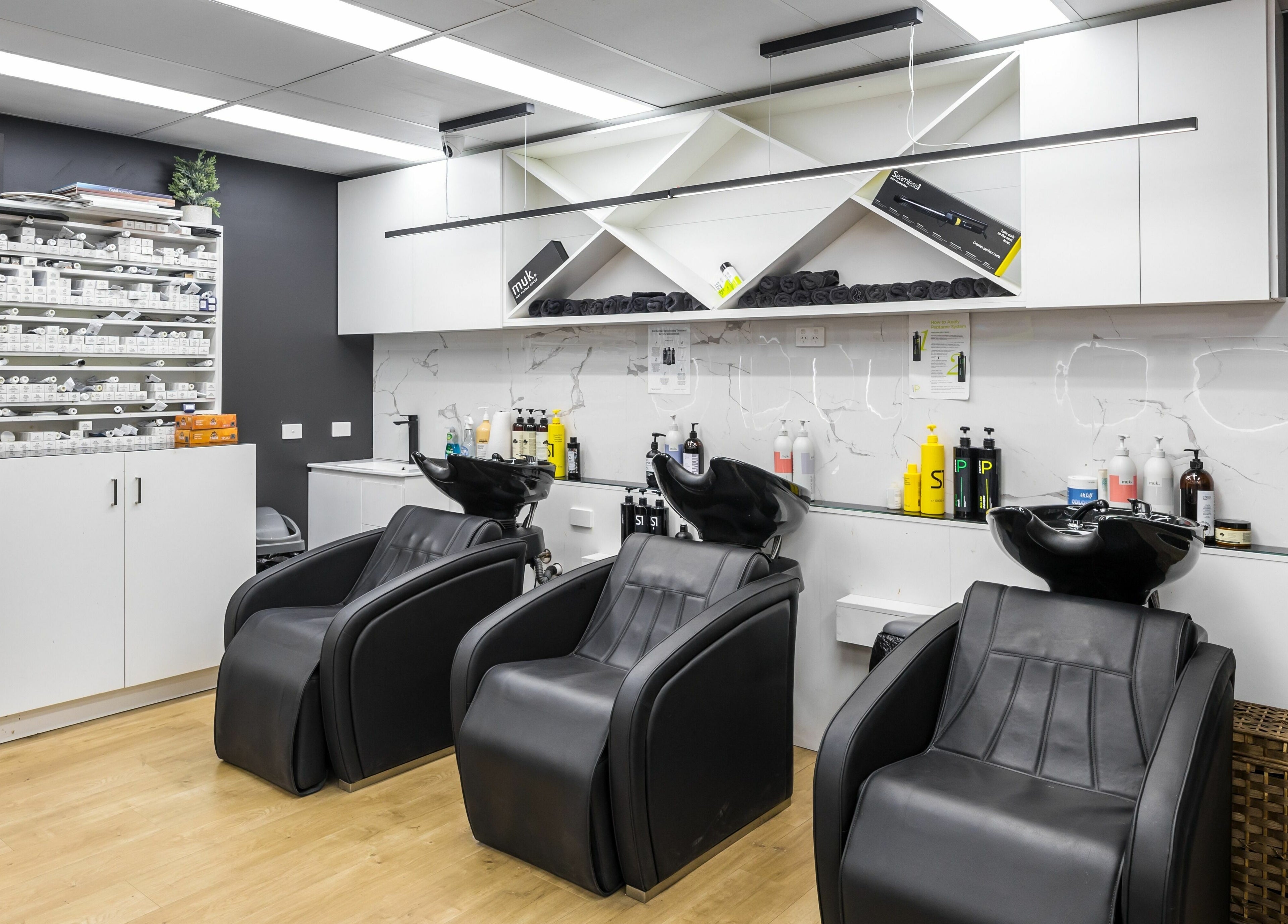 Modern salon wash area at V.I Hair, Melbourne, Victoria, AU featuring sleek black chairs and stylish cabinetry.