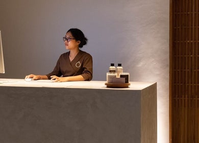 Receptionist at Koya Spa Seminyak in Bali, Bali, ID, seated at a modern desk with spa products.